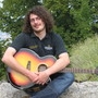 Joe mit Gitarre sitzend in der Landschaft 5